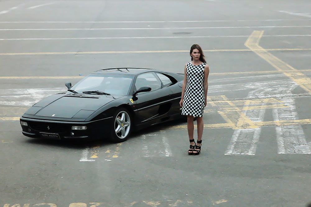 Black Ferrari F355 berlinetta with woman standing next to it